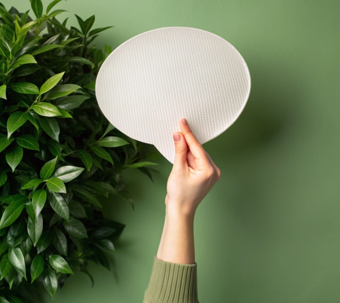person-holding-paper-disc-their-hand-against-green-wall (1)